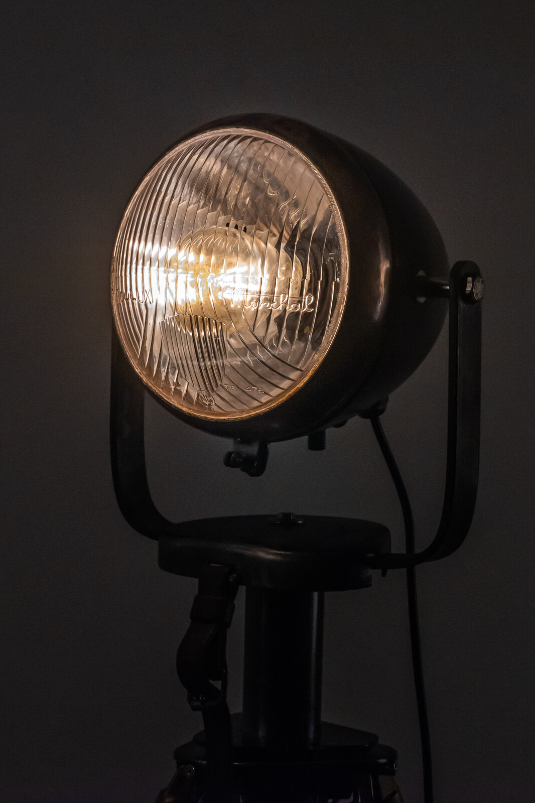 Phare allumé dans la pénombre, lettrage gravé sur le verre strié du réflecteur